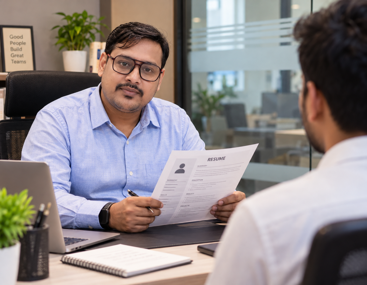An HR manager taking an interview of a fresher at an office desk